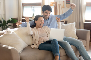 Unbelievable. Excited happy young spouses laughing and yelling full of joy getting email of winning...