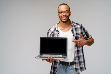 A young african american man holding laptop pc and showing at blank screen