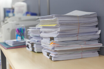 Pile of documents on desk stack up high waiting to be managed