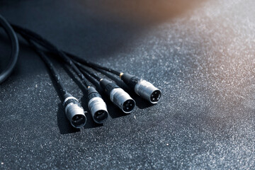 In preparation for a concert, the audio cables stand on a black podium. Close-up