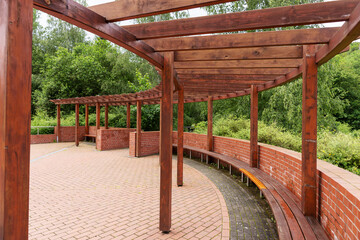 Fototapeta na wymiar New round wooden pergola with long bench in the park