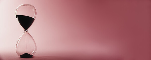 Hourglass on a pink background, long banner. Urgency and running out of time concept