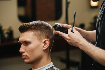 Confident young man in a barber shop getting a trim