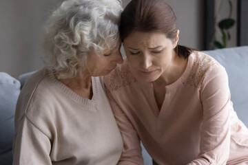 Close up loving mature woman mother comforting frustrated grownup daughter, hugging, sitting on...