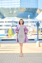 Trendy woman in lilac coat and dress with stripes