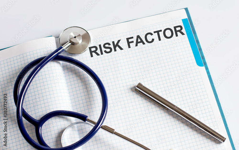 Poster paper with text risk factor on a table with stethoscope