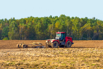 Fototapeta na wymiar Farmer in tractor preparing land with seedbed cultivator as part of pre seeding activities, farmland