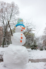 Snowman in the winter city park. Christmas holiday mood