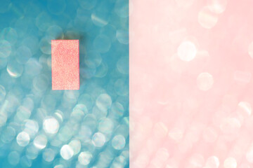 Glitter gift box on pink and AI Aqua 2021 color split backdrop. Festive flat lay with magic lights