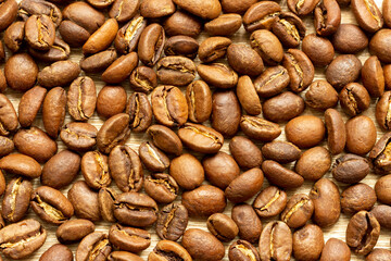 Roasted arabica coffee beans scattered in a heap on the table.