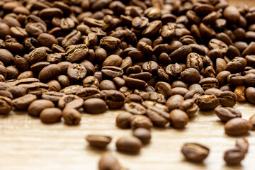 Roasted arabica coffee beans scattered in a heap on the table.