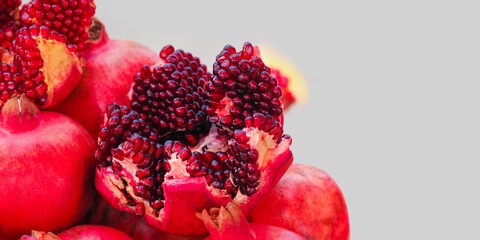 Ripe garnet, punica granatum. Half pomegranate and whole pomegranates on light background, panoramic view, copy space
