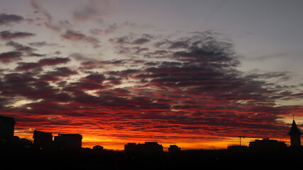 Fire sunrise with hazy clouds and buildings. Hazy clouds fire sunrise.