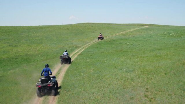 Aerial, tracking, people on ATVs in an empty green landscape, WY, USA