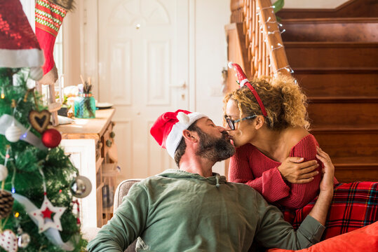 Kiss and love with adult couple during christmas holiday season time at home - concept of life together and happiness at 40s and 50s years old - happy lifestyle man and woman kissing and loving indoor