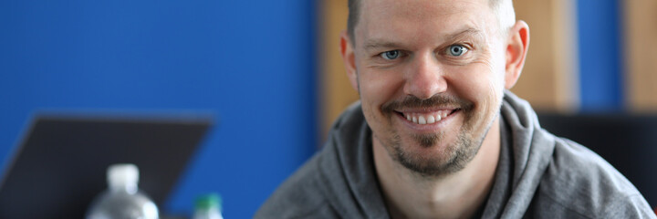 Portrait of smiling cheerful middle-aged male posing on camera indoors. Happy person wearing grey hoodie. Copy space in left side. Modeling and happiness concept