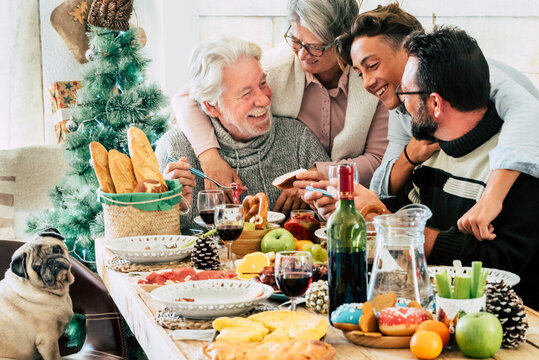 Family Group People Enjoy Lunch Together In Christmas Days Season - Happy Caucasian Enjoy Food And Indoor Leisure Activity At Home During Holidays Time - Mixed Generations Young To Old