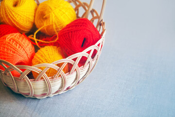 Wicker basket with needlework on table. Basket with colorful skeins of yarn, tangles, copy space