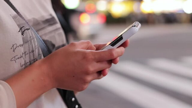 夜の渋谷でスマホを操作する若い女性の手元
