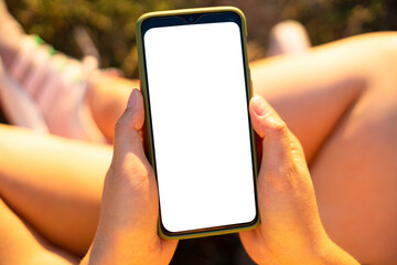 Woman hands holding black mobile phone with blank screen sitting in the park. Remote control concept. Online training for students. Online shopping