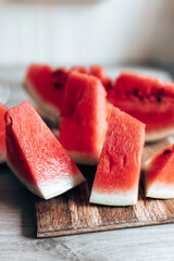Ripe pieces of watermelon on a wooden cutting board in the kitchen. Vertical photo orientation....