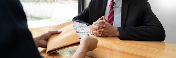 Businessman reciving money United States Dollars bills to corruption from his partner in business at working desk - bribery concept.