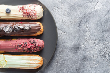 Set of different eclair cakes on dark backgrouns, copy space