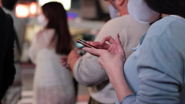 夜の渋谷でスマホを操作する若い女性の手元