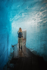 Fototapeta na wymiar junge Frau läuft durch eine Eishöhle des Rhonegletschers in den Schweizer Alpen