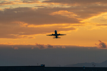 夕焼けの中を上昇する航空機