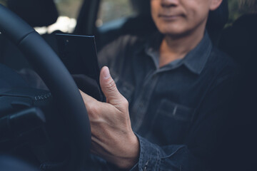 Asian middle age man using mobile smart phone inside a car