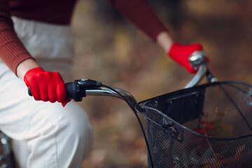 Young woman riding bicycle in red gloves and face mask at autumn park