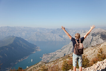 Traveler with backpack on mountain top. Happy man with raised arms in autumn landscape. Tourist...