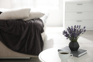 Beautiful lavender flowers, cup of coffee and book on white table indoors. Space for text