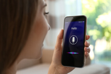 Woman using voice search on smartphone indoors, closeup