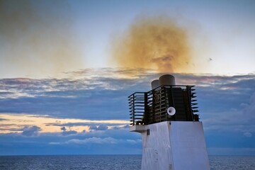 Closeup of funnel of a cargo ship floating in the Baltic sea with smoke polluting environment...