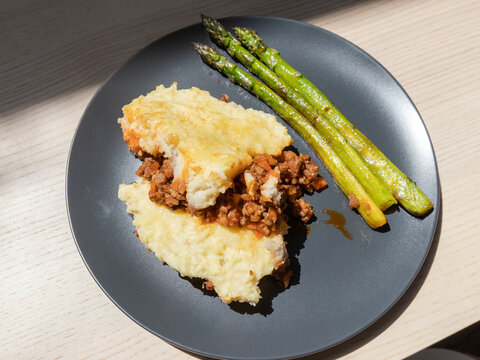 A plate of Hachis Parmentier (Shepherds Pie) with asparagus on the side.