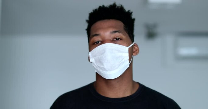 Young black man putting and adjusting surgical face mask