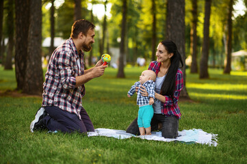 Mother, father and little baby play in summer park