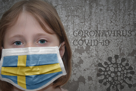Little girl in medical mask with flag of sweden stands near the old vintage wall with text coronavirus, covid, and virus picture. Stop virus concept