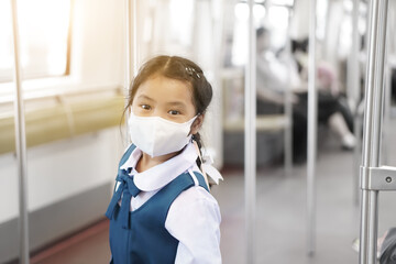 Asian child student or kid girl smile wear face mask to protect covid-19 in sky train or railways...