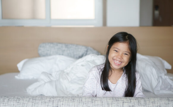 Asian Child Cute Relax Or Kid Girl Happy Smile And Beautiful White Teeth To Wake Or Woke Up In Morning On White Bed And Pillow In Bedroom At Family Home On Holiday And Vacation Or Dental Background