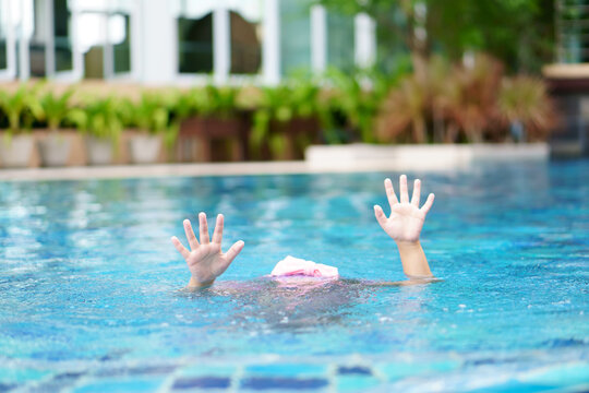 drowning child or kid girl and people cannot swim to deep water and raise two hand for help on swimming pool and near death