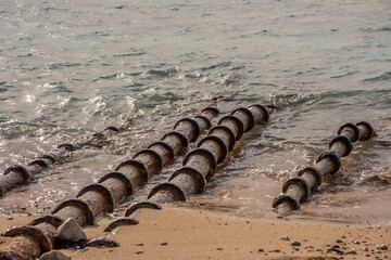 Pipes on the sandy seashore against the background of the sea