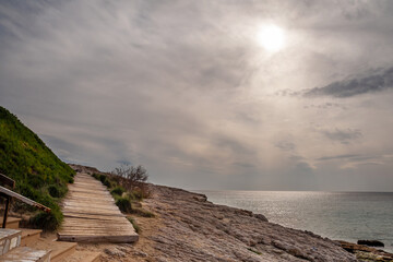 Walkway on the stone seashore against the background of the sea