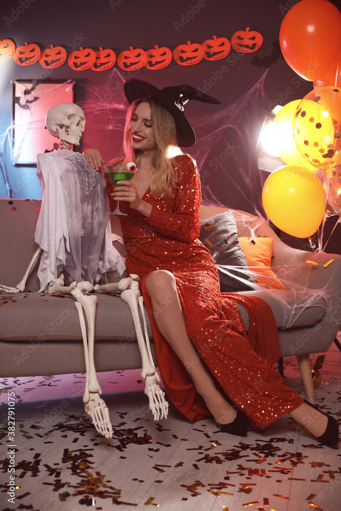 Sticker Woman in witch hat sitting near skeleton on sofa indoors. Fun Halloween party