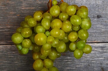 A large bunch of yellow green grapes on a wooden board background. ripe juicy green grapes, copy space