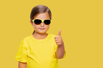 Cheerful Little Girl wearing sunglasses Happy Smiling Studio Concept. yellow background and clothing. isolated 