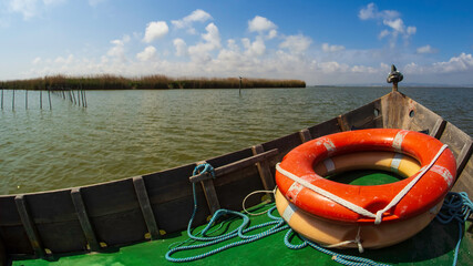 Barca de madera con dos salvavidas navegando por la aguas del Parque Natural de la Albufera de Valencia
