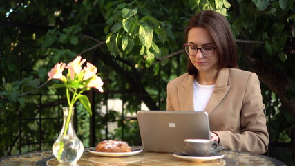 Young business woman sits in a cafe and works at a laptop.